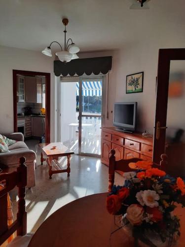 a living room with a tv and a table with flowers at Mi bonito apartamento del Portil in El Portil