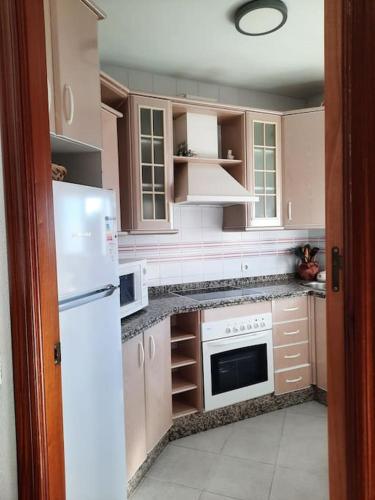 a kitchen with white appliances and a white refrigerator at Mi bonito apartamento del Portil in El Portil