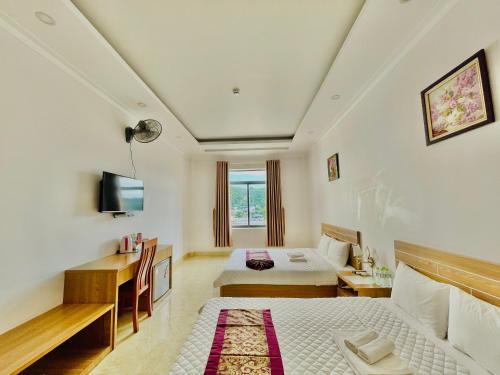 um quarto de hotel com duas camas e uma televisão em Chau Gia Hotel em Vinh Hy