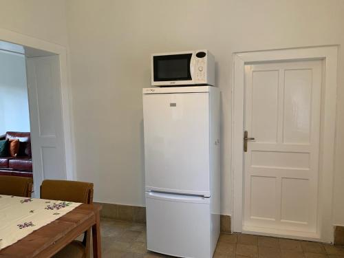 a white refrigerator with a microwave on top of it at Hazmarmar in Csernely