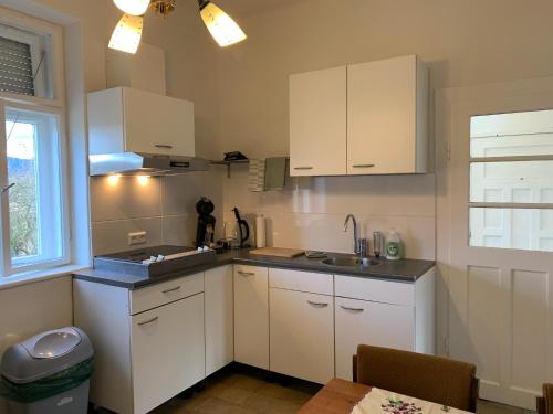 a kitchen with white cabinets and a sink and a window at Hazmarmar in Csernely