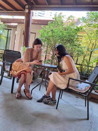 two women sitting at a table looking at their phones at Baan Songjum in Chiang Mai