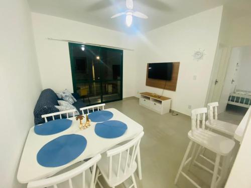 una sala da pranzo con tavolo e sedie bianchi di Apartamento beira mar vista para montanha em Massaguaçú a Caraguatatuba