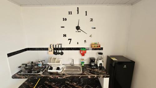 une horloge sur un mur au-dessus d'un comptoir de cuisine dans l'établissement Family Amazon Minimalist, à Leticia
