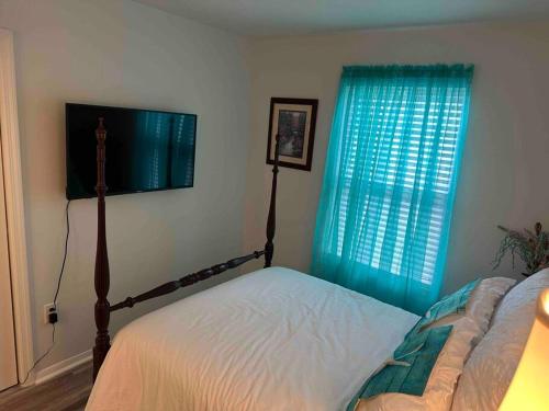 a bedroom with a bed and a window with blue curtains at Chesapeake Holiday House in Port Republic