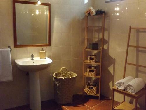 een badkamer met een wastafel, een spiegel en een plank bij Casa do Lêntejo - Casas de Taipa in São Pedro do Corval