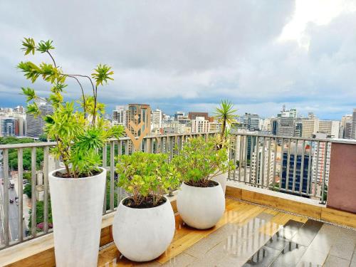 Tres jarrones blancos con plantas en un balcón en ELEGANCE SUÍTES VERGUEIRO en São Paulo