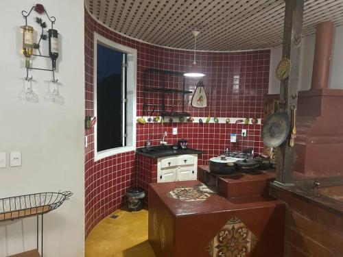uma cozinha com uma parede de azulejos vermelhos em Casa Temporada recanto de minas em Tiradentes