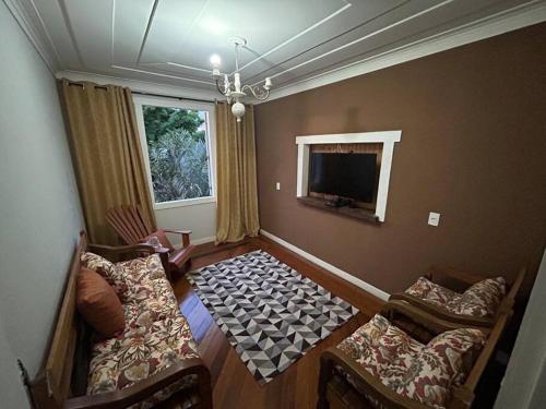uma sala de estar com duas cadeiras e uma televisão em Casa Temporada recanto de minas em Tiradentes