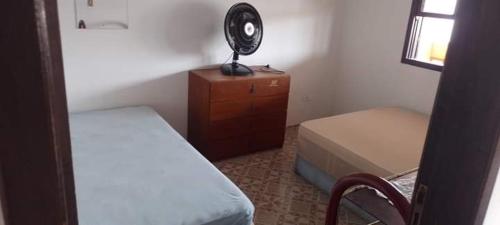 a bedroom with a bed and a desk with a fan at Solar Dona Irma in Guaratuba