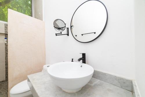 un bagno con un lavandino bianco e uno specchio di Relaxing 2 bedroom apartement in the center of tulum with private pool and terrace a Tulum