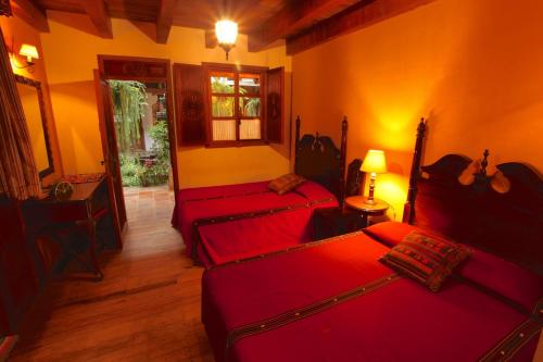 a room with two beds in a room with yellow walls at Hotel Candelaria Antigua in Antigua Guatemala