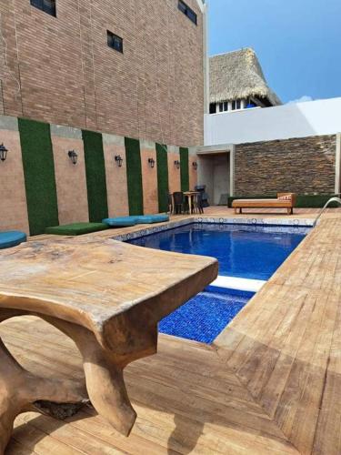 a swimming pool with a wooden table next to a building at Cabaña Maria in Santa Marta