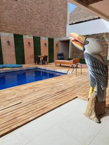 una estatua de un pájaro sosteniendo un frisbee junto a una piscina en Cabaña Maria, en Santa Marta