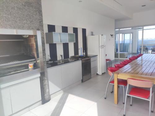 a kitchen with a wooden table and red chairs at Excelente Vista al Golf y al Mar in Mar del Plata