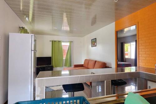 eine Küche mit einer Theke mit einem Sofa und einem Kühlschrank in der Unterkunft Vaiana Home 1 in Taputapuapea