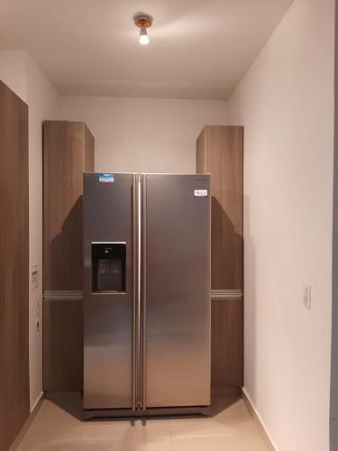 um frigorífico de aço inoxidável num quarto com armários de madeira em Las Margaritas em Villavicencio