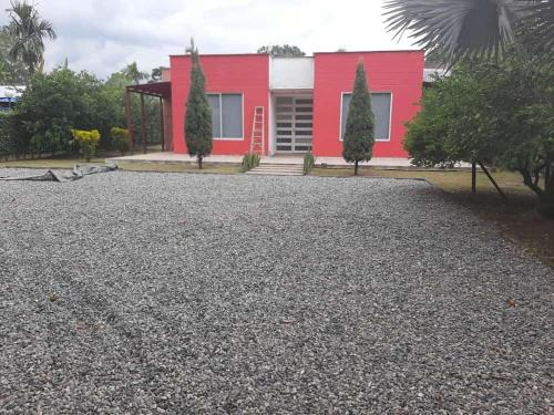 uma casa vermelha com uma entrada de cascalho em frente em Las Margaritas em Villavicencio