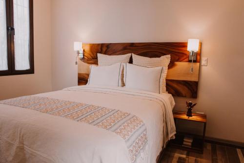a bedroom with a large white bed with a wooden headboard at Bärehuus Boutique Hotel in Antigua Guatemala