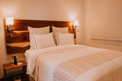 a bedroom with a large bed with white sheets and pillows at Bärehuus Boutique Hotel in Antigua Guatemala