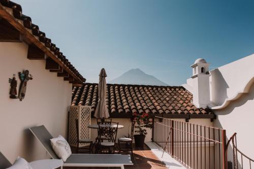 a balcony with a table and chairs and a roof at Bärehuus Boutique Hotel in Antigua Guatemala