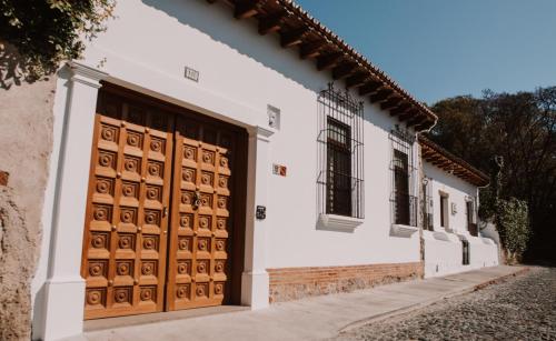 a white building with wooden doors on a street at Bärehuus Boutique Hotel in Antigua Guatemala