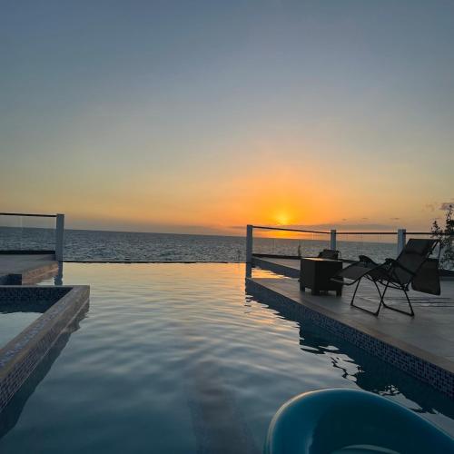 a pool with a table and a chair next to the ocean at Oceanview lux Villa + Infinity pool, Chef & Butler in Kings Pen