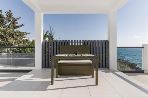 a table and a chair on a patio with the ocean at Oceanview lux Villa + Infinity pool, Chef & Butler in Kings Pen