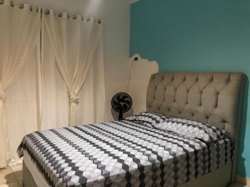 a bedroom with a bed with a black and white checkered blanket at Quarto Duplo Costa brava in Guarujá