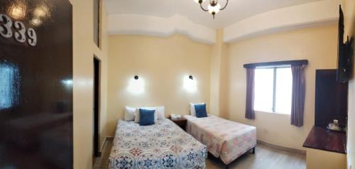 a bedroom with two beds and a window at Hotel Sevilla in Guatemala