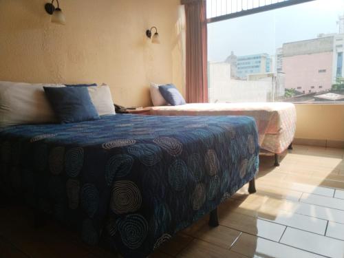 グアテマラシティにあるHotel Sevillaのベッドルーム1室(ベッド2台、大きな窓付)