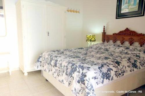 um quarto com uma cama com um cobertor azul e branco em Casa ÍSIS de aluguel por temporada em Capão da Canoa com piscina em Capão da Canoa