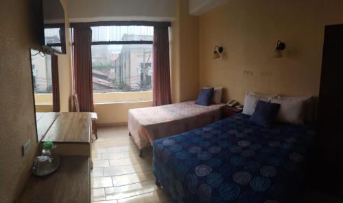 a hotel room with two beds and a window at Hotel Sevilla in Guatemala