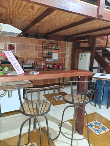a wooden table with two bar stools in a room at Casa de Praia - meu lugar em Iriri in Anchieta