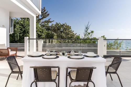una mesa blanca con sillas en el patio en Oceanview lux Villa + Infinity pool, Chef & Butler, en Kings Pen