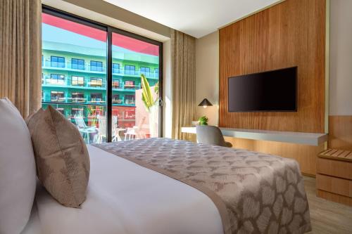 a hotel room with a bed and a large window at voco Dubai Monaco, the Heart of Europe by IHG in Dubai