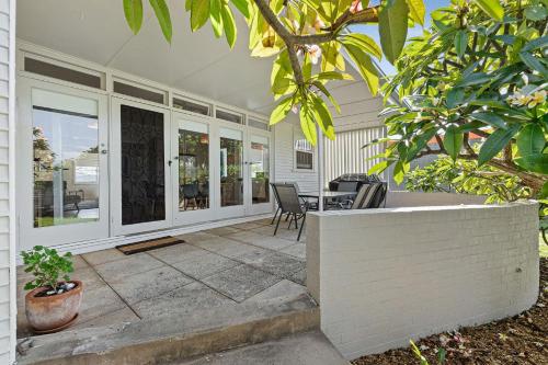 a home with a patio with a table and chairs at Narooma Lighthouse Cottage - 74 Princes Highway Narooma in Narooma