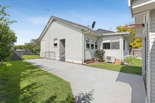 a white house with a driveway in a yard at Narooma Lighthouse Cottage - 74 Princes Highway Narooma in Narooma