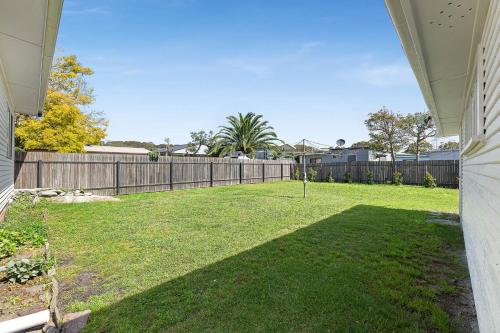 a backyard with a fence and a grass yard at Narooma Lighthouse Cottage - 74 Princes Highway Narooma in Narooma