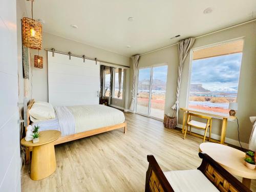 a bedroom with a bed and a desk and windows at Page Arizona border town- Tranquil Zen Retreat with Amazing Mesa Views in Big Water