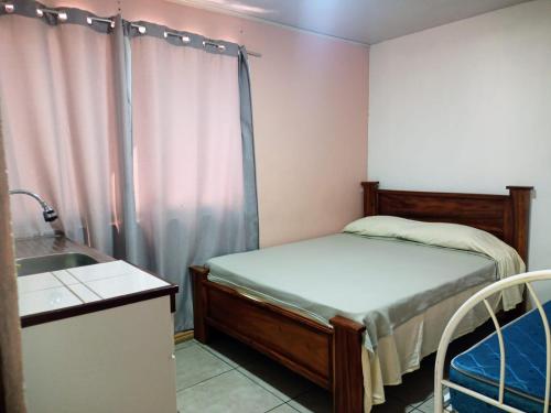 Dormitorio pequeño con cama y lavamanos en Hogar tico-estadounidense cerca de aeropuerto, en Alajuela