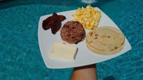 een bord met ontbijt op een tafel in een zwembad bij Hotel La Pradera del Arenal in Fortuna