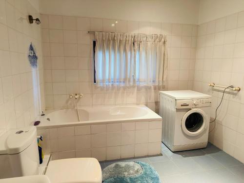 a bathroom with a tub and a washing machine at Haus Berlin in Negombo