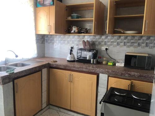 een keuken met houten kasten, een wastafel en een fornuis bij Serene villa in Jinja