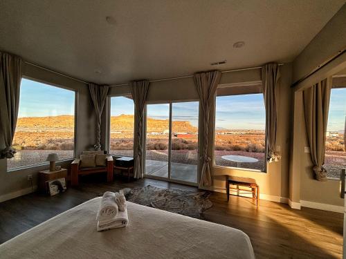 a bedroom with a large bed and large windows at Canyon Oasis suite with Grand Mesa view in Big Water