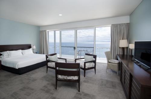 a hotel room with a bed and a table and chairs at Grand Pacific Hotel in Suva
