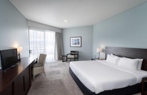 a hotel room with a large bed and a television at Grand Pacific Hotel in Suva