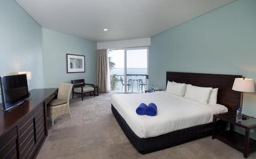 a hotel room with a bed with blue shoes on it at Grand Pacific Hotel in Suva
