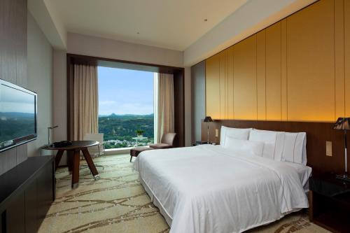 um quarto de hotel com uma cama grande e uma janela grande em The Westin Sendai em Sendai