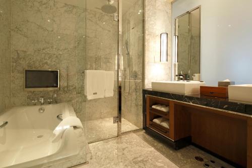 a bathroom with a tub and a sink and a mirror at The Westin Sendai in Sendai